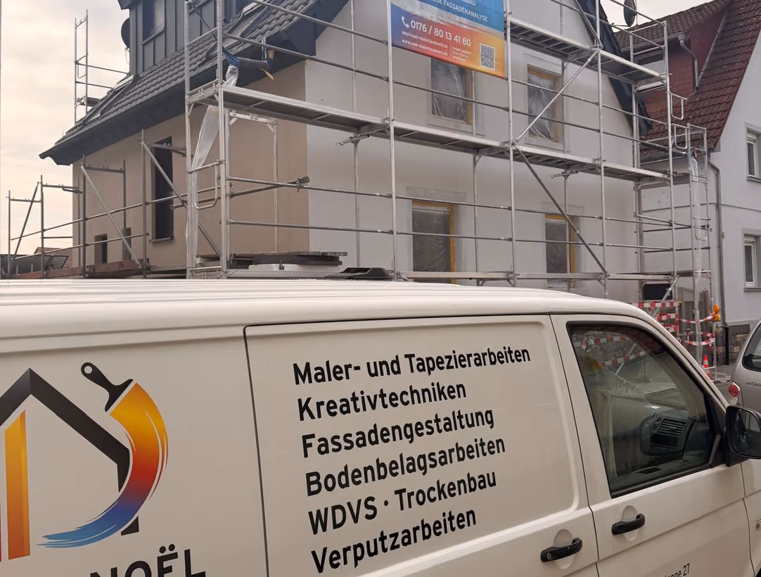 Firmenwagen von Patrick Noël Malerhandwerk vor einem eingerüsteten Wohnhaus während der Fassadenarbeiten
