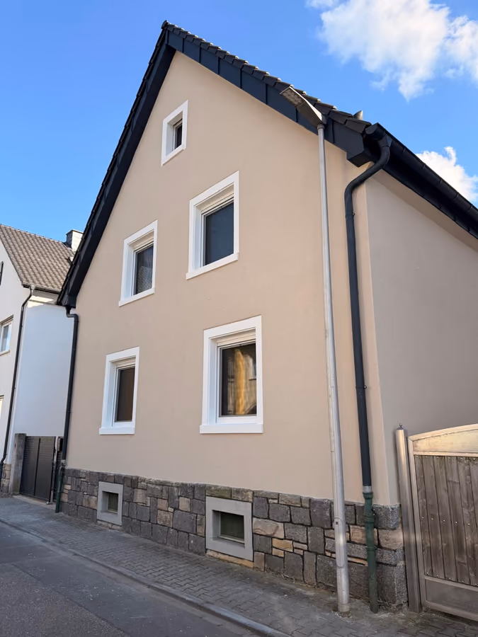 Giebelseite eines Wohnhauses nach der Fassadenerneuerung mit weißen Fensterfaschen