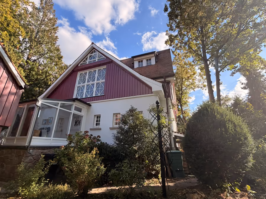 Referenzobjekt: Villa mit roter Holzverschalung, weißem Putz und Wintergarten
