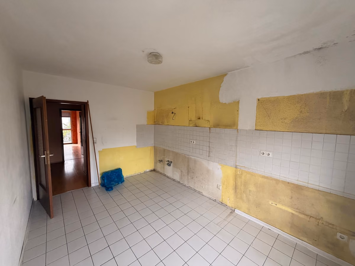 Küche nach dem Ausbau der Küchenzeile mit Flecken, Farbresten und offenen Anschlüssen an der Wand