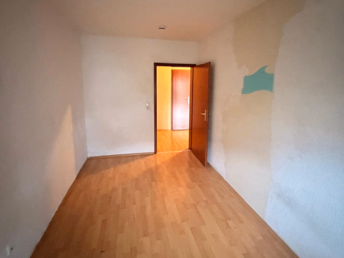 Schmales Zimmer vor der Renovierung mit abgelösten Stellen und Farbresten an der Wand